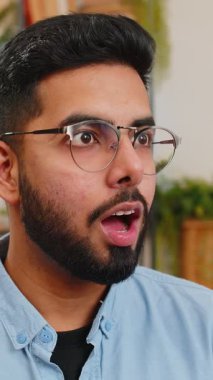 Şok olmuş gözlüklü Hintli adamın portresi. Evdeki oturma odasında ağzın açık kalmış. Büyük gözlü mutlu Arap adam ani zaferle heyecanlandı, iyi haber..