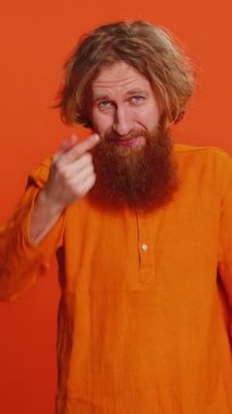 Sen delisin, aklın yerinde değil. Kafası karışmış beyaz bir adam kamerayı işaret edip aptalca bir jest yapıyor, aptalın birinden delice bir plan yapmasını istiyor, zorbalık yapıyor. Kızıl saçlı genç adam turuncu arka planda izole edilmiş..