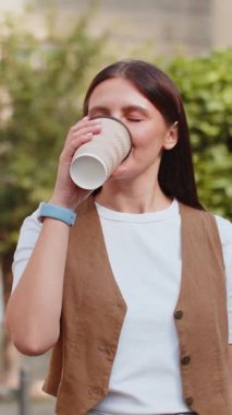 Kafkasyalı genç ve güzel bir kadın sabah kahvesinin tadını çıkarıyor sıcak bir şeyler içiyor ve dışarıda gülümsüyor. Dinleniyorum, ara veriyorum. Şehir merkezi caddesinde yürüyen ve kahve içen bir kız. Kasaba yaşam tarzları.