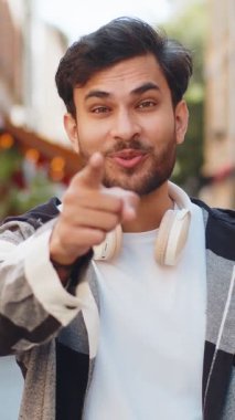 Hey sen! Genç Hintli turist heyecanlı bir şekilde gülümsüyor ve kamerayı işaret ediyor. Şanslı mutlu kazananı seçiyor. Bu da seni harika gösteriyor. Şehir caddesinde duran yakışıklı Arap adam. Yaşam Tarzları.