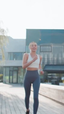 Atletik koşucu kadın, akıllı koşucunun bileklik takmasına bakar. Zaman, kalp atışı, nabız, koşu sırasında SPO2. Genç kız güneşli şehir parkında kardiyo yapıyor..