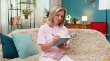 Evde orta yaşlı hamile bir kadın parmak kaldırıyor ve bebek ismi fikrini parlak bir gülümsemeyle günlüğe yazıyor. Kanepede oturan beyaz kız yaratıcı kıvılcımlardan hoşlanır. Bebeğin adını not eder. Mutlu bir umut hisseder..