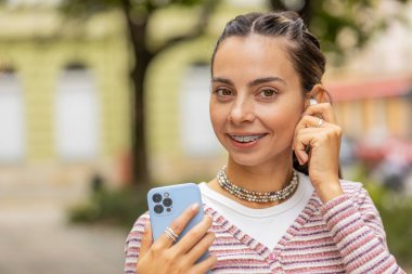 Kablosuz kulaklıklı mutlu, gevşemiş kız dışarıda dans eden en sevilen disko rock n roll müziğini seçiyor. Dişlerinde diş teli olan genç ve güzel bir kadın. Şehir caddesinde duruyor.