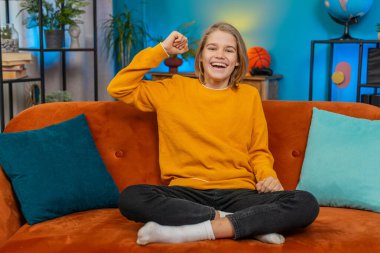 Beyaz çocuk, evdeki koltukta görevini tamamladıktan sonra heyecan gösteriyor. Zaferi kutladığımı haykırarak en sevilen spor takımına tezahürat yapan ve neşe saçan TV izlerken