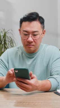 Asyalı adam kanepede oturur ve cep telefonu tebessümleri kullanır. Orta yaşlı Çinli bir adam akıllı telefon sosyal medya uygulamaları üzerinden rahatlama filmi izlerken mesajlarını paylaşıyor.