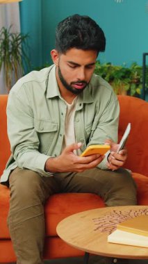 Planlama bütçesi. Zengin mutlu Hintli adam akıllı telefon hesap makinesi uygulamasıyla para sayıyor, evdeki faturaları hesaplıyor. Kazancından memnun olan adam, planlı tatil hediyeleri için para biriktirir.