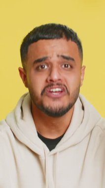 Gerginlikten bağıran sinirli Hintli adam korku, umutsuzluk, şaşkınlık şokun öfkesini ve kavgasını hisseder. Sarı stüdyo arka planında izole Arap genç adam