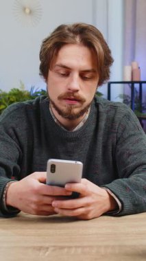 Üzgün, Kafkasyalı bir adam akıllı telefon daktilo kullanıyor, aniden piyango sonuçlarını şaşırıyor, kötü haber, servet kaybı, son teslim tarihi, virüs. Masadaki ofisteki genç yetişkin adam.