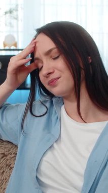 Evde ağır baş ağrısı çeken genç hasta bir kadın var. Kanepede oturuyor ve başı çok yorgun. Kafkasyalı kız umutsuzca arıyor ve ağrı kesici alıyor, derinden sıkıntılı ve yorgun.