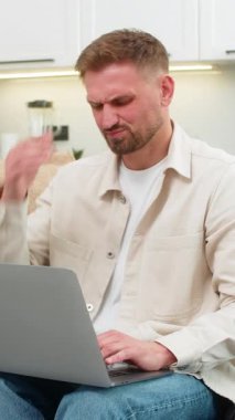 Evdeki genç adam dizüstü bilgisayar kullanıyor. Baş ağrısı hissediyor. Şakakları okşuyor, gözleri kapıyor ve nefes alıyor. Kanepedeki beyaz adam işi durdurur, kafa masajı yapar, şakaklara masaj yapar, stres yorgunluğu çeker, dinlenir ve nefes alır..