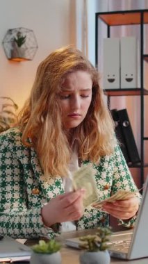 Kafkasyalı serbest çalışan genç bir kadın nakit parasız sayıyor. Finansal kriz. İflas. Yoksulluk ve yoksulluk. Ev ofis masasında oturan dizüstü bilgisayarı olan kadın iş kadını..