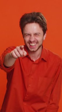 Komik anekdotları duyduktan sonra kahkahalarla gülen, komik şakalara tepki veren, dertsiz tasasız bir genç adam. Pozitif insanlar. Yakışıklı adam stüdyo turuncu arka planda izole edilmiş.