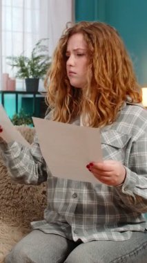 Gergin bir şekilde belgeleri yırtan genç bir kadın, olumsuz sonuçlardan hayal kırıklığına uğramış ve hayal kırıklığına uğramış görünüyor. Kafkasyalı kızıl saçlı kız duygusal olarak sıkıntılı, başarısızlık ya da istenmeyen sonuç yüzünden üzgün.