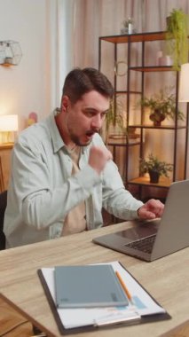 Dizüstü bilgisayar ağı üzerinde çalışan mutlu beyaz adam ani zafer, galibiyet, gol başarısı ve iyi bir kariyer haberiyle şok oldu. İş yerinde yumruklarını sıkan heyecanlı, serbest çalışan bir adam. Dikey.