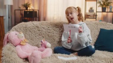 Genç kız, oyuncak pelüş figürleri evdeki kanepenin önüne yerleştiriyor ve basit matematik aritmetiğini tekrarlıyor. Çocuk çocuk ara sıra kahkahalar atar. Sahte otorite tarafından eğlendirilir. Aptal öğretmen rolü.