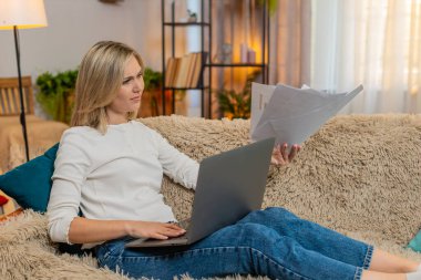 Orta yaşlı bir kadın evdeki kanepeye dizüstü bilgisayarın yanına belgeler atar ve sinirle el sallar. Yetişkin bir kadın stresli çalışma seanslarında hayal kırıklığı ve duygusal çöküntü yaşar..