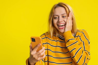 Mutlu Kafkasyalı genç kız akıllı telefon daktilo kullanıyor bağırarak evet de büyük ikramiye kazan iyi haber piyango hedefi başarıyı kutla, sarı ile oyun kazan