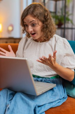 Sinirli, genç, beyaz bir kadının bilgisayar kamerasıyla kanepe ya da erkek arkadaşından memnun olmayan bir arkadaşla görüntülü konuşma yapması ve gergin, konuşan, sorunlu çatışma stresi tartışmasını çözmesi. Dikey.