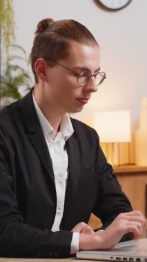 Beyaz takım elbiseli genç işadamının portresi dizüstü bilgisayarda çalışırken parmağını sallıyor ve 