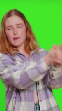 Genç bir kadın parmak tabancasıyla etrafta dolanıyor, kendinden emin görünüyor, seçim yapıyor, tabancayla hedefi vuruyor. Yeşil krom anahtar arka planında izole edilmiş bir kız. Reklam.