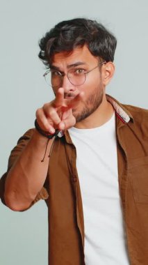 Gözüm üzerinde. Gözlerine ve kamerasına bakan özgüvenli adam, seni birini gözetlerken izlediğimi göster. Yakışıklı, hayal kırıklığına uğramış Hintli adam gri stüdyo arka planında izole edilmiş.