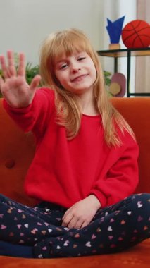 Kameraya gülümseyen ve el sallayan genç kız merhaba, merhaba, merhaba ya da güle güle diyerek misafirperver bir yüz ifadesiyle karşıladı. Oturma odasındaki beyaz çocuk kanepede oturuyor.