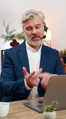 Merkez ofisteki orta yaşlı işadamı, müşteriyle konuşurken kulaklık takıyor. Masadaki serbest çalışan adam hızlı çözüm öneriyor. Yüksek hizmet derecesini ve sadakati arttırıyor..