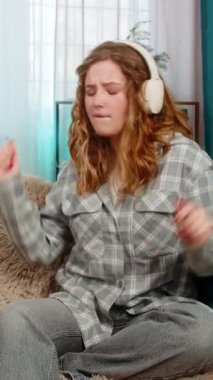 Evde kulaklık takan genç bir kadın. Gözleri kapalı. Nazikçe dans ediyor ve favori müzikten hoşlanıyor. Kafkasyalı kızıl saçlı kız kanepenin üzerinde ritme göre hareket ediyor, neşe, duygusal huzur ve rahatlama hissediyor.