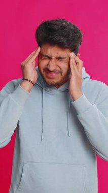 Memnun olmayan Hintli Hintli adam baş ağrısı problemini tedavi etmek için tapınakları ovuyor, tansiyon, migren, stres, ekşitme, acı içinde kıvranıyor, pembe arka planda yalnız başına izole edilmiş yüksek tansiyon