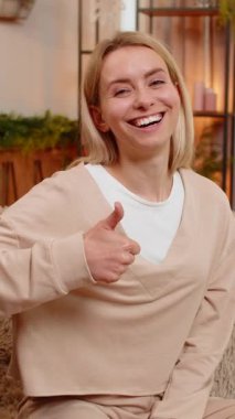 Genç yetişkin bir kadın başparmağını kaldırır ve koltukta gülümseyerek tatmin olduğunu ifade eder. Sarışın kız, neşeli hareketler sergiliyor. Açık enerji ve neşeli ruh haliyle olumlu tepki veriyor.