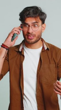 Sinirli, stresli Hintli genç adam iki cep telefonuyla bağırarak konuşuyor. Tartışıyorlar. Şikayet anlaşmazlığı çözülüyor. Gri arka planda izole Arap adam