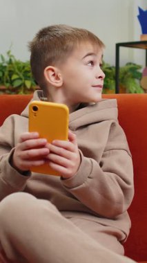 Akıllı telefon sosyal medya uygulamaları üzerinden rahatlama filmi izlerken mesajlaşan genç çocuk. Beyaz bir erkek çocuk evde cep telefonu kullanıyor. Oturma odasında, koltukta oturuyor.