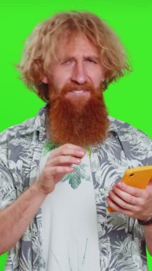 Üzgün adam akıllı telefon daktilo kullanıyor. Oyun oynuyor, kaybediyor. Ani piyango sonucu şaşırıyor. Krom anahtar arka planında izole edilmiş kızıl saçlı adam.