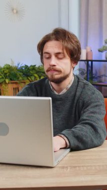 Kafkasyalı serbest çalışan yorgun bir adam dizüstü bilgisayar kullanıyor, baş ağrısı, tansiyon, migren, evde stres yaşıyor. Adam defter üzerinde çalışıyor, e-posta gönderiyor, online alışverişler yapıyor, film izliyor.