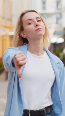 Hoşlanmamak. Kafkasyalı kadının işaret dilini göstermesi hoşnutsuzluğunu belirterek tatminsiz kötü iş hatasını dile getiriyor. Şehrin güneşli caddesinde duran hoşnutsuz kadın.