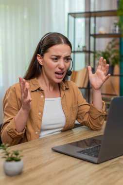 Masasında oturan genç bir kadın diz üstü bilgisayarla hızlı bir şekilde konuşuyor kulaklık takıyor ve müşteriyle sohbet ederken sinirleniyor. Beyaz kız kaşlarını çatar ve keskin bir şekilde konuşur. Gerginlik ve destek rolünde hayal kırıklığı gösterir.