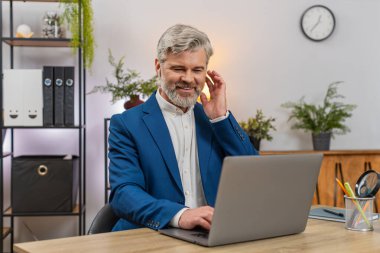 Ev ofisteki orta yaşlı iş adamı dizüstü bilgisayarda kulaklık takıyor, projeye odaklanırken müzik dinliyor. Masadaki serbest çalışan adam, yazılım dağıtım kodlarının ritmini seviyor..