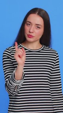 Tartışma. Rahatsız ve hoşnutsuzlukla el kol hareketi yapan, başarısızlıktan dolayı azarlayan, bunun neden olduğunu soran genç bir kadın. Esmer, çekici kız, mavi stüdyo arka planında izole edilmiş.