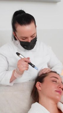 Beyaz bir kız mikronize dermapen ve vitamin enjeksiyonları kullanarak saç büyümesini canlandırmak için kafa derisi tedavisi görüyor. Saç restorasyonu için kozmetoloji kliniğinde trikoloğun uyguladığı prosedür.