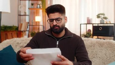 Evdeki Hintli adam zarfı açıyor, mektubu okuyor ve kötü haberlere üzülüyor, üzüntüyle tepki veriyor. Arap adam, iş, kredi veya sınav sonuçlarının reddedilmesi yüzünden hayal kırıklığına uğramış bir şekilde koltukta oturuyor..