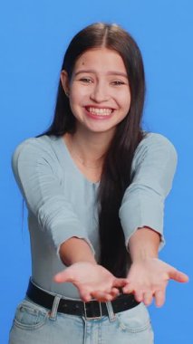 Bedava hediyeler ve hediyeler. Kafkasyalı genç bir kadın ellerini açıyor, heyecan, hazırlama sürprizi, aşk duygularını paylaşıyor, tebrik ediyor, bağış yapıyor. Genç kız mavi arka planda izole edilmiş.