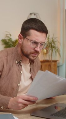 Stresli genç işadamı ödenmemiş banka borçlarına bakıyor, evrak işleriyle uğraşıyor, bütçe planlaması ipotek ödemelerini hesaplıyor. Serbest çalışan adam ofis masasına kağıt para atıyor.