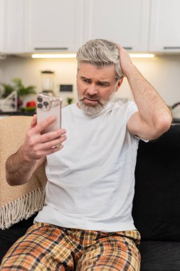 Evde akıllı telefondan konuşan orta yaşlı bir adam başarısız bir oyun oyunu ya da iş inkar haberlerini izler ve kafasını sallar. Kanepede oturan olgun bir adam gözlerini indirir derin derin nefes alır ve duyguları sakinleştirmeye çalışır ve sonucu kabullenmeye çalışır.