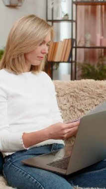 Orta yaşlı bir kadın evdeki kanepeye dizüstü bilgisayarın yanına belgeler atar ve sinirle el sallar. Yetişkin bir kadın stresli çalışma seanslarında hayal kırıklığı ve duygusal çöküntü yaşar..