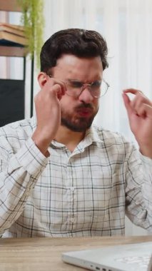 Göz yorgunluğu ve baş ağrısından muzdarip çok çalışan genç Hintli sakallı iş adamı ofis masasında dizüstü bilgisayarda çalışıyor. Yorgun serbest çalışan gözlüğünü ve masajını çıkarıyor, burun köprüsünü ovuyor..