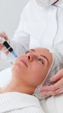 Orta yaşlı bir kadın dermapen ile mikro cilt terapisi görüyor. Kozmetik uzmanı modern estetik güzellik kliniğinde kız cildinin gençleşmesi için nazikçe mezoterapi uyguluyor.