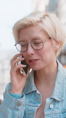 Telefon, iyi haber, dedikodu. Akıllı telefondan hoş sohbetler yapan mutlu beyaz bir bayan, açık havada arkadaşlarıyla konuşmaktan zevk alıyor. Şehir caddesinde modaya uygun giyinmiş bir kız. Kasaba yaşam tarzları.