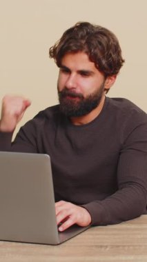 Mutlu Hintli adam işini bitirdikten sonra bilgisayarı kapatıyor. Çevrimiçi çalışan serbest çalışan bir adam, masa başında uzaktan çalışan. E-öğrenme, internette gezinme. Bej renkli stüdyo geçmişi olan rahat bir adam.