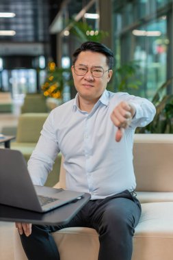 Hoşlanmamak. Ofis lobisinde dizüstü bilgisayarla çalışan üzgün bir işadamı işaret dilini gösteriyor, hoşnutsuzluğunu, memnuniyetsizliğini ve kötü işini ifade ediyor. Otel odasında hoşnutsuz ciddi bir adam var..