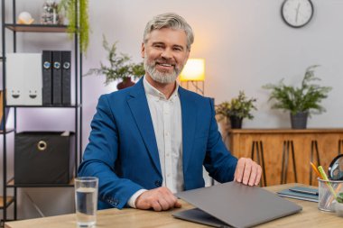 Merkez ofisteki orta yaşlı işadamı projesini bitirdikten sonra dizüstü bilgisayarını kapatıp kameraya gururla bakıyor. Masadaki serbest çalışan adam gülümsüyor. Bugün elde ettiği başarıyı yansıtıyor. Kendine güveni tam..